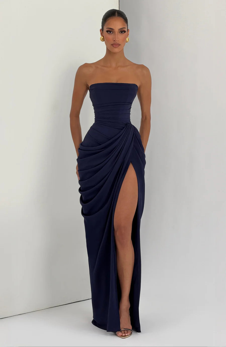 Navy ruched strapless maxi dress in full-length view, draped skirt with thigh-high slit on leg