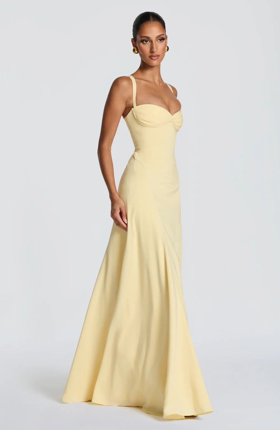 Side view of pale yellow corset maxi dress with fitted bodice, sweetheart cups, and flowing hem