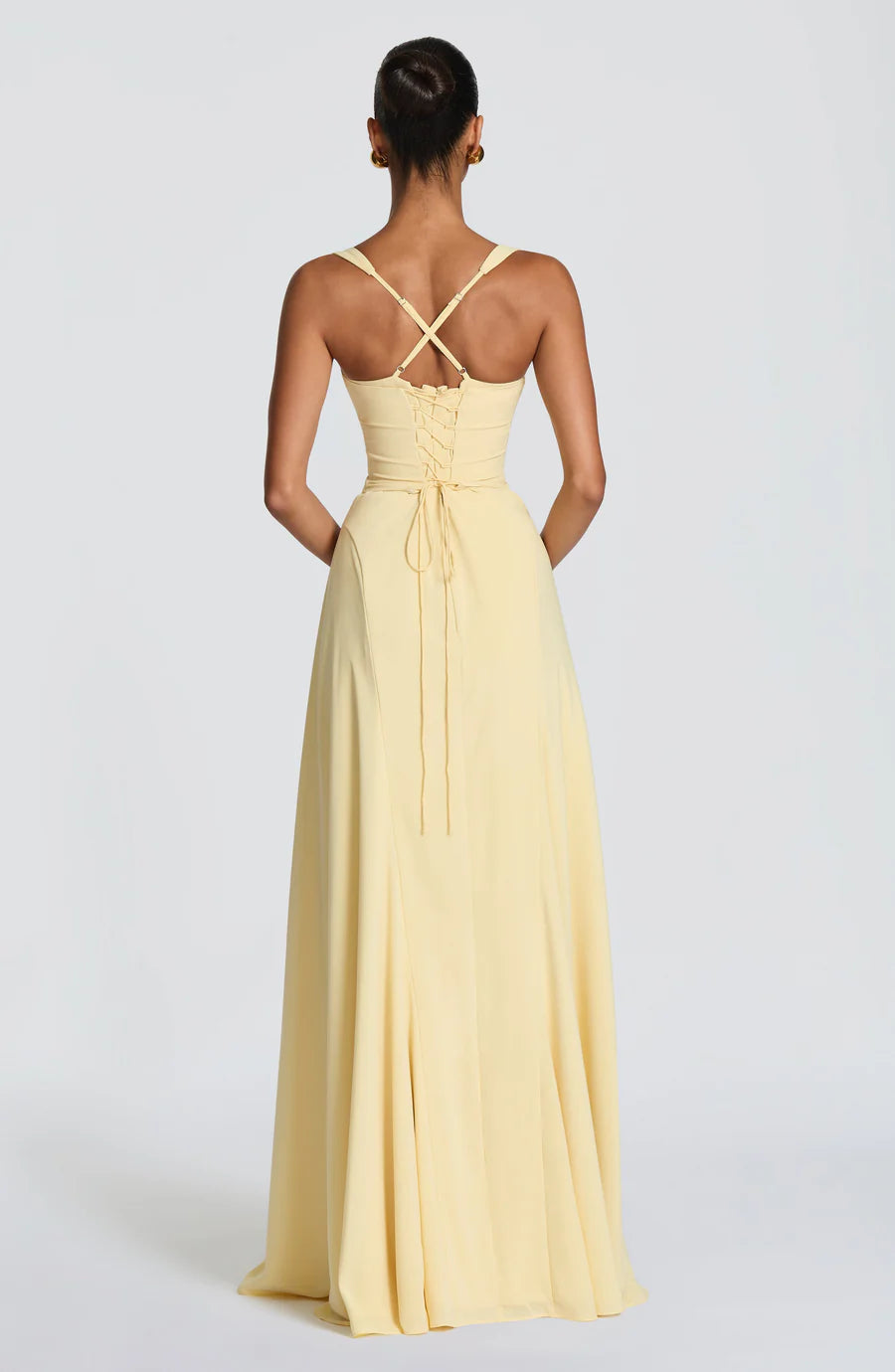 Back view of yellow corset maxi dress with lace-up bodice, long ties, and crisscross straps