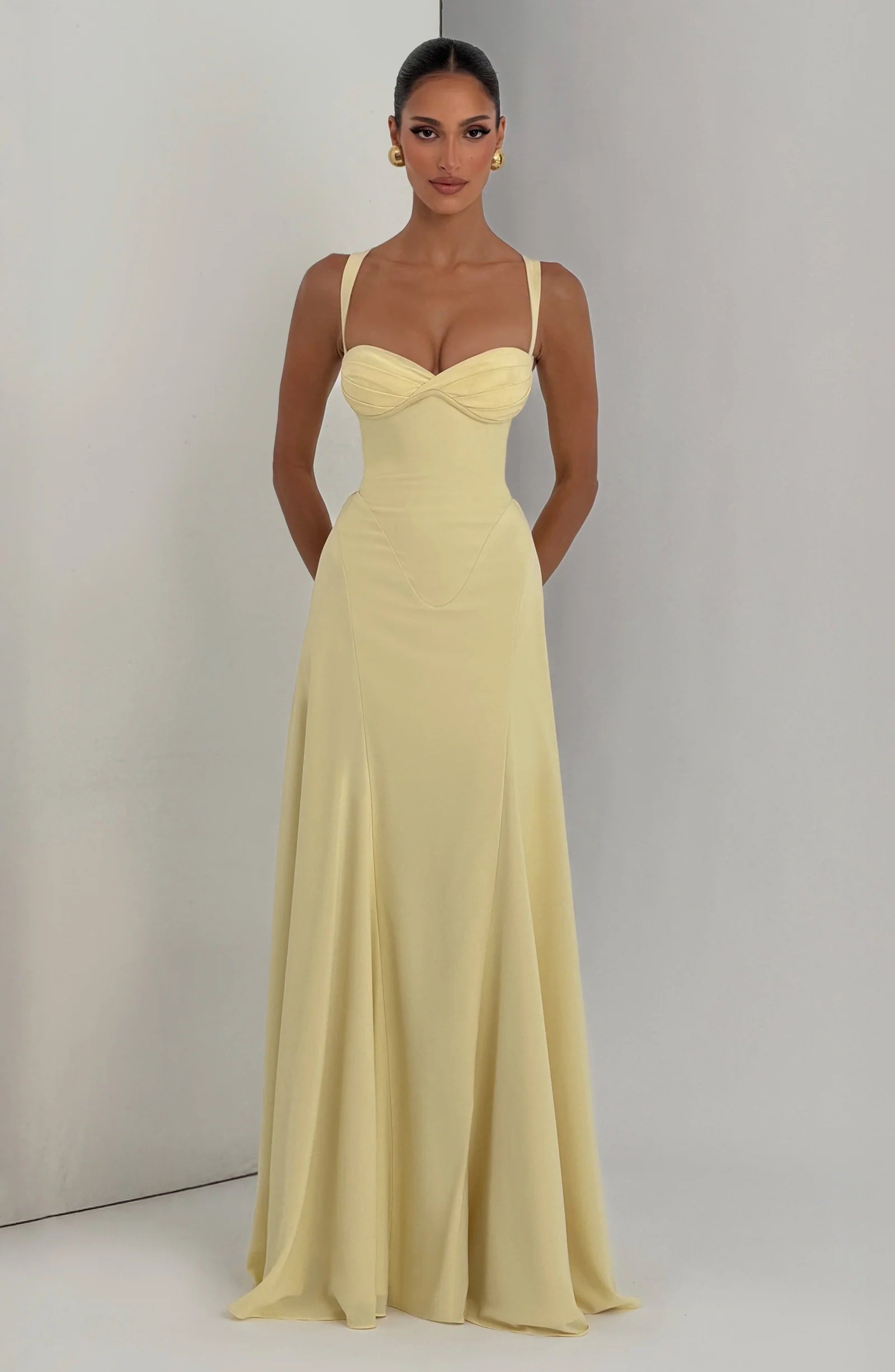 Front view in studio of pale yellow corset maxi dress with sculpted waist seams and full skirt