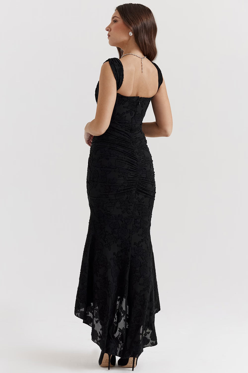 Back view black corset midi dress with fitted waist, ruched back detail, and sheer floral hem panel