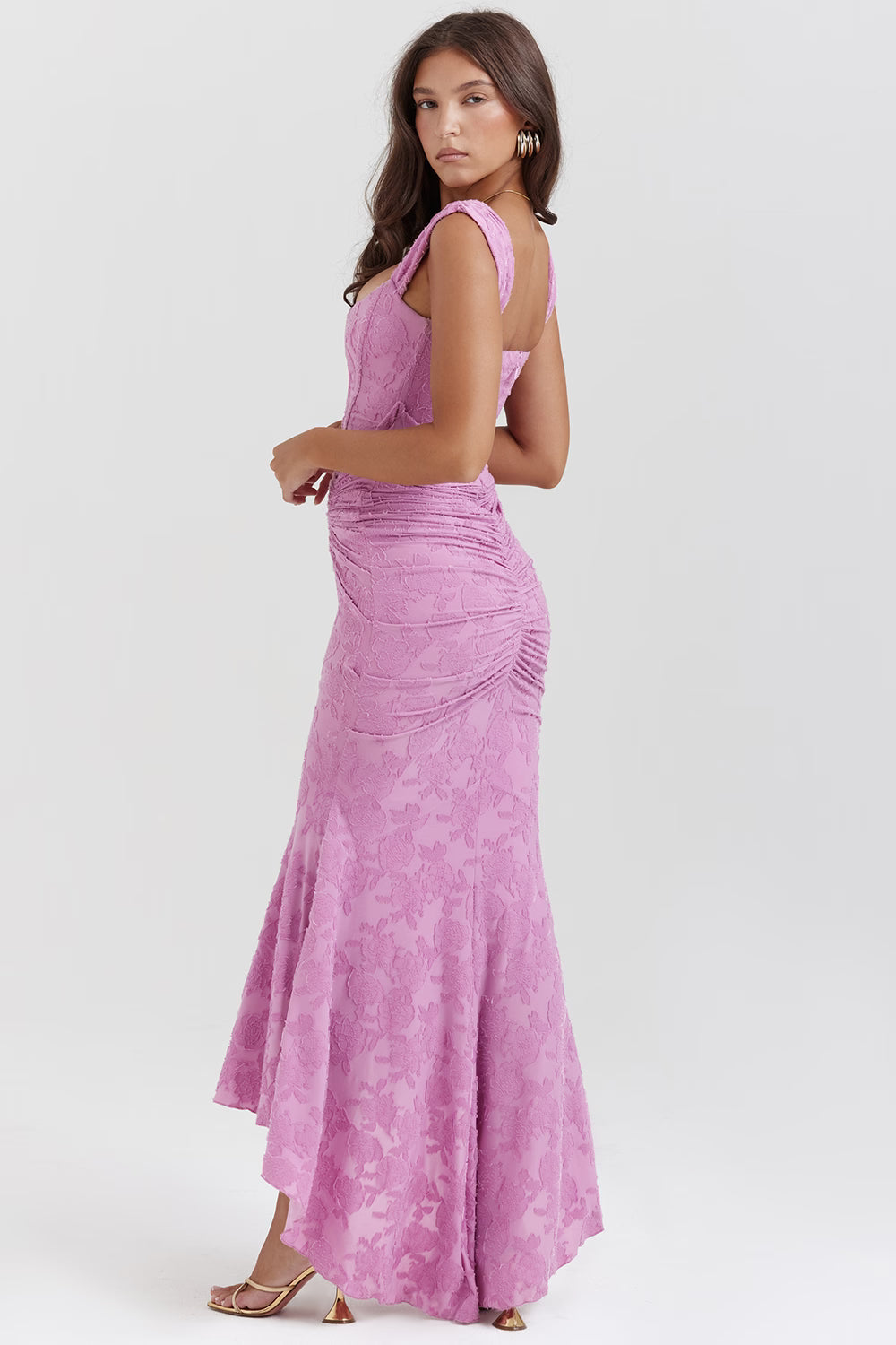 Three-quarter back view of pink corset midi dress showing fitted bodice, ruching and high-low skirt