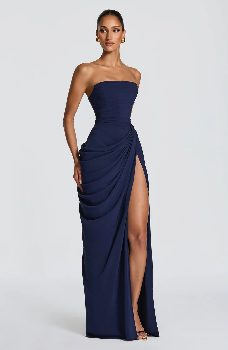Front view of navy ruched maxi dress, strapless neckline with gathered waist drape and side slit