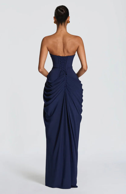 Back view of navy strapless maxi dress featuring lace-up corset back and ruched draped skirt