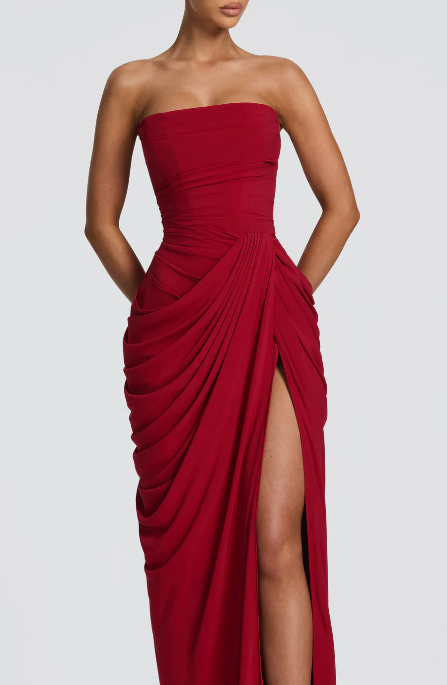 Close-up of red strapless ruched maxi dress showing draped pleats and high side slit detail