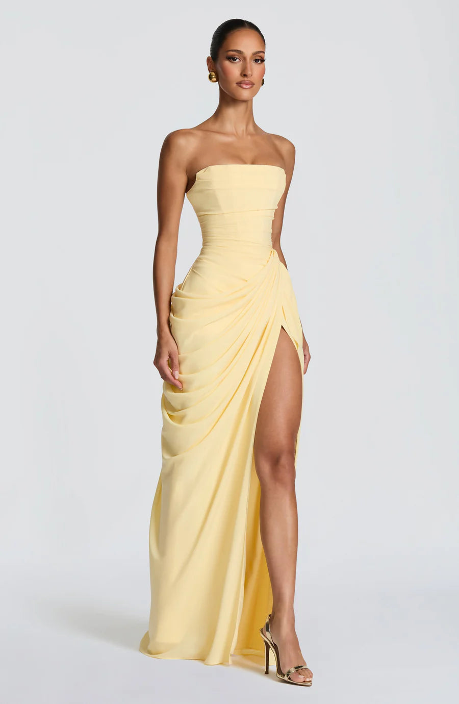 Three-quarter view of yellow strapless ruched maxi dress with drape ruching and thigh-high slit