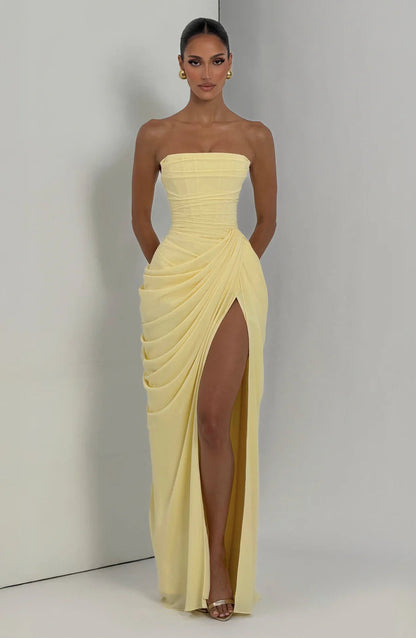 Full-length yellow ruched maxi dress with strapless neckline and side slit, shown in studio corner
