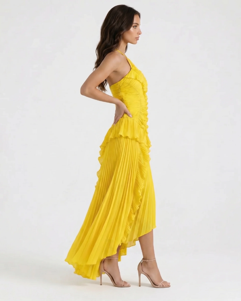 Profile view of yellow pleated maxi dress with cascading ruffles down front and flowing asymmetrical skirt
