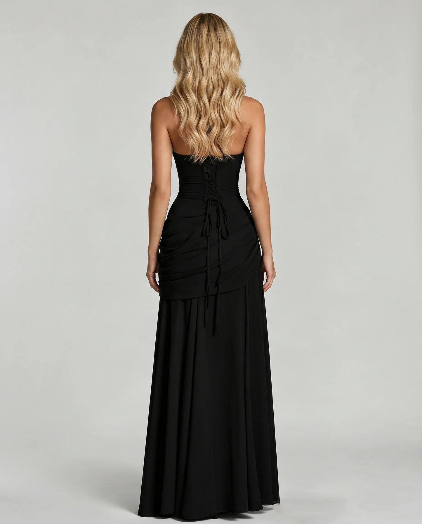 Back view of black ruched maxi dress with lace-up corset detail and long tie at center back