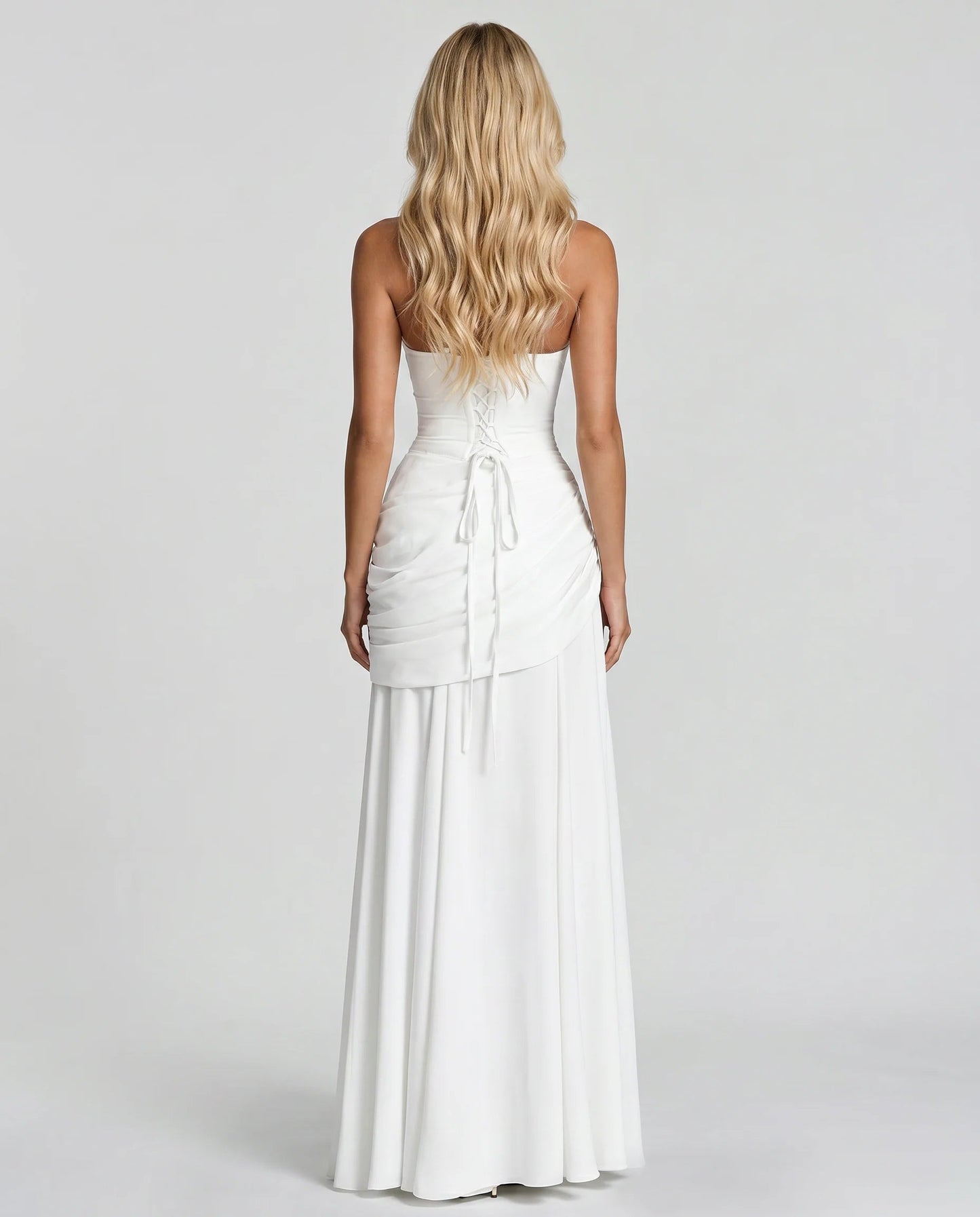 Back view of white ruched maxi dress with lace-up corset tie and flowing skirt