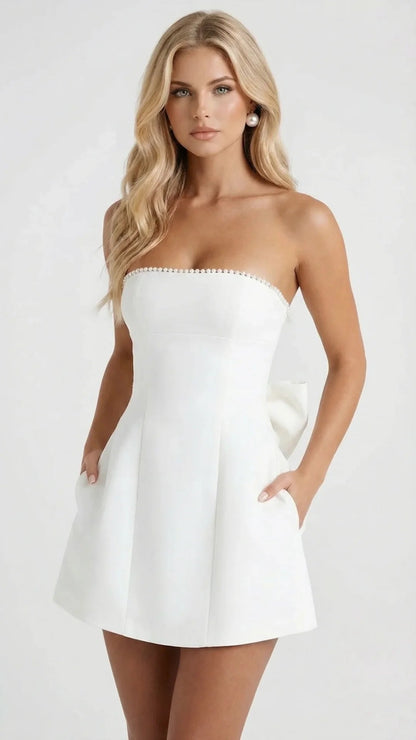 White strapless pearl trim mini dress with structured bodice and pockets, front close view