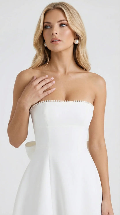 Close-up of white strapless mini dress showing pearl beaded neckline detail and fitted bodice