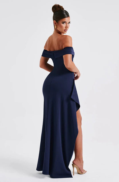 Back 3/4 view navy off-shoulder maxi dress with long flowing skirt and side drape detail