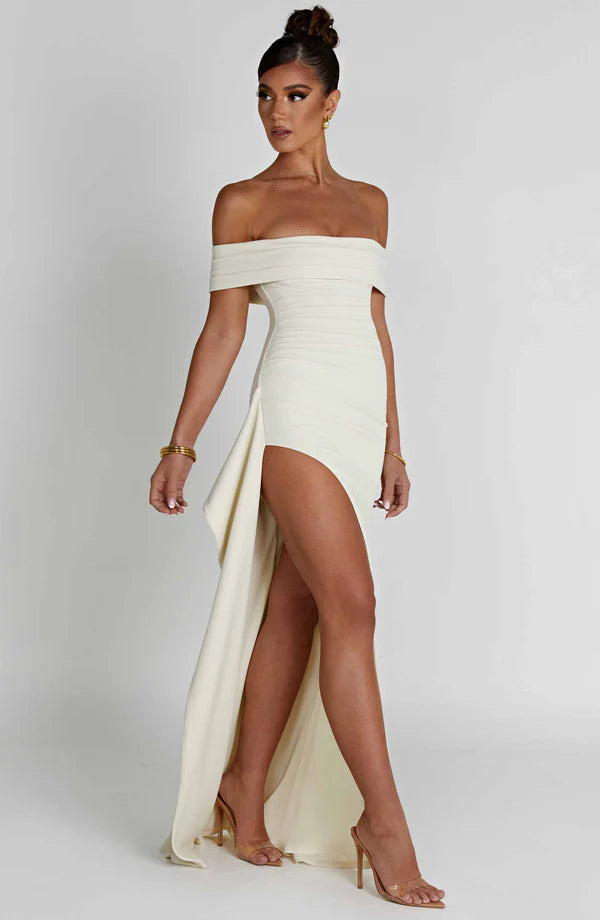 Side angle of white ruched off-shoulder maxi dress showing high slit and flowing sash detail