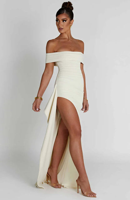Side angle of white ruched off-shoulder maxi dress showing high slit and flowing sash detail