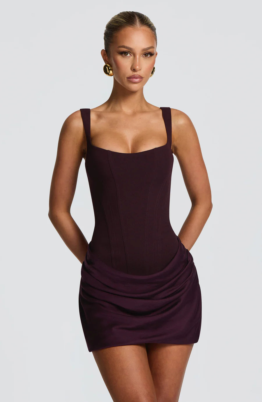 Studio mid-length view of purple corset mini dress showing bodice seams and ruched mini skirt