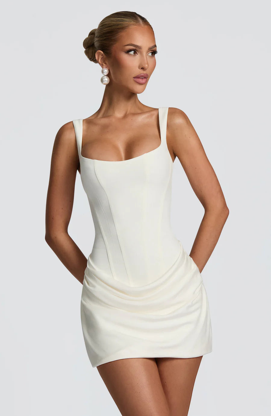 Close-up of white corset mini dress showing square neckline, wide straps, and contoured seams