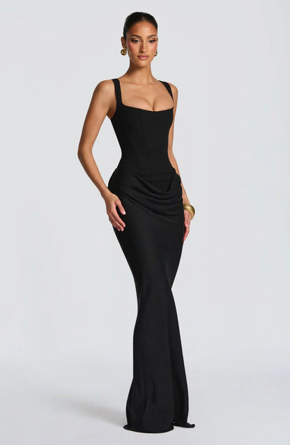 Angled side view of black maxi dress highlighting the draped hip overlay and sleek column silhouette