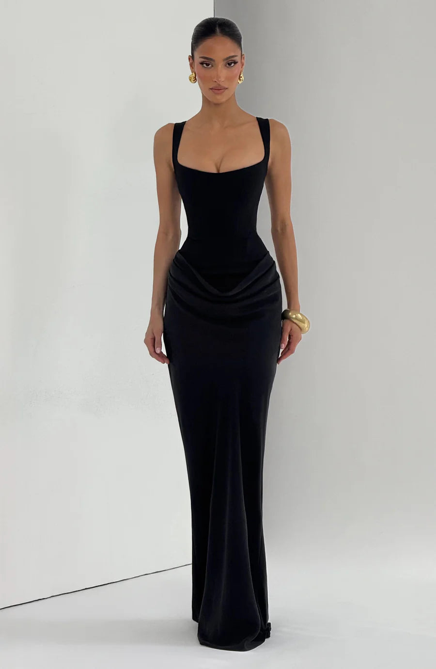 Full-length black draped maxi dress with square neckline and softly gathered hip draping in studio lighting