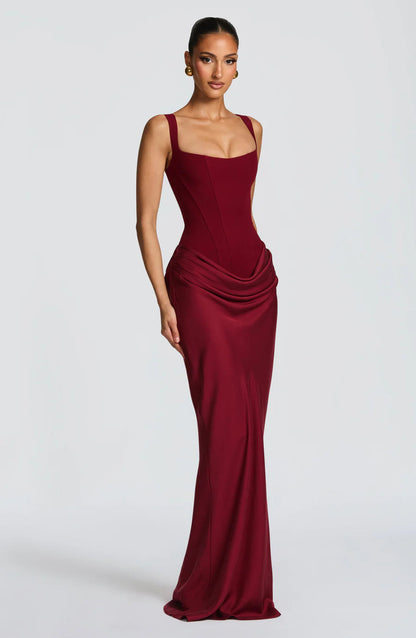 Three-quarter view of burgundy maxi dress with wide straps and draped hip overlay