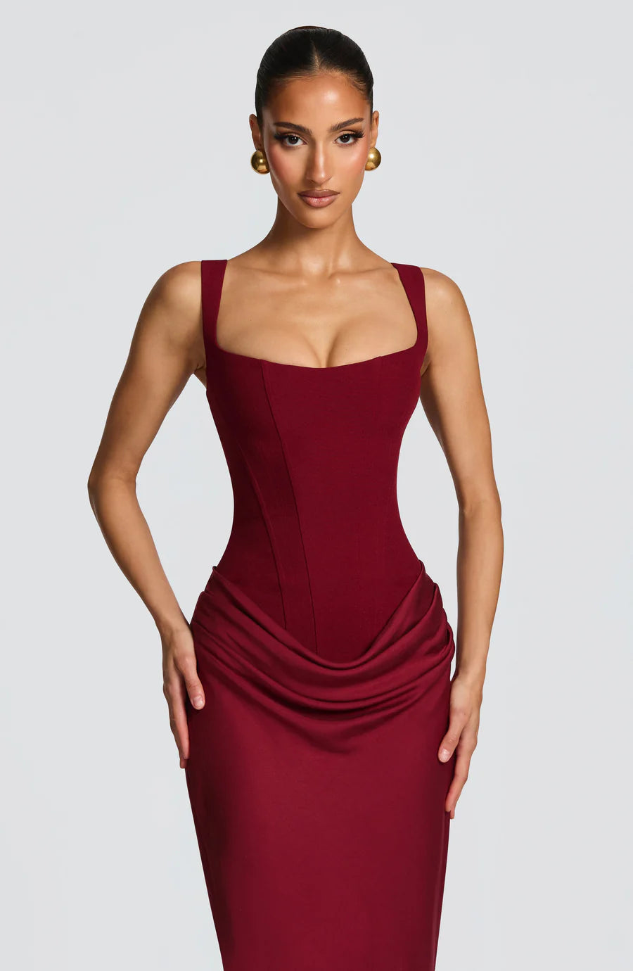 Close-up of burgundy corset-style bodice with square neckline and gathered drape at hips