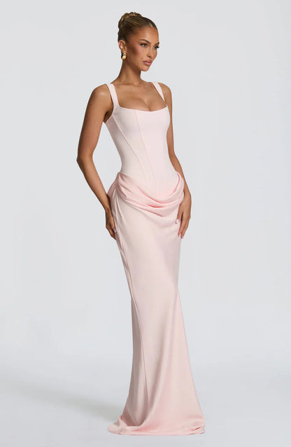 Angled side view of blush pink maxi dress featuring draped hip detail and long skirt