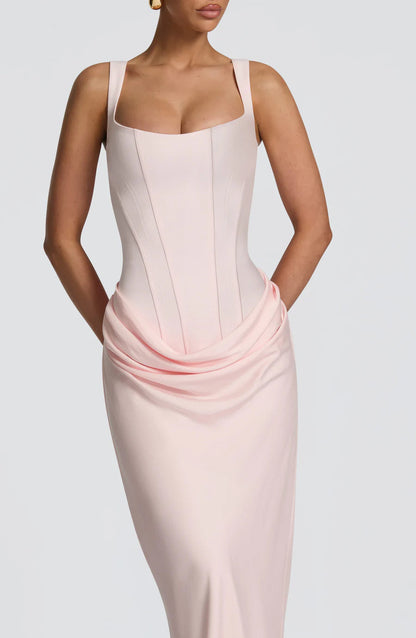 Close-up of blush pink maxi dress showing structured corset seams and draped waist overlay