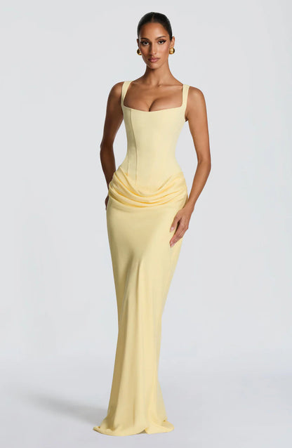 Three-quarter front view of yellow maxi dress with fitted corset top and gathered hip drape