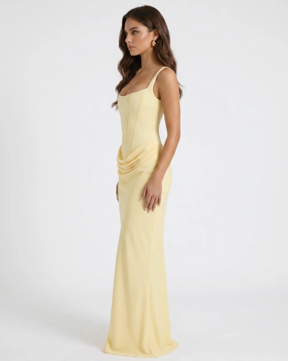 Side view of yellow draped maxi dress with structured bodice, wide straps, and floor-length hem