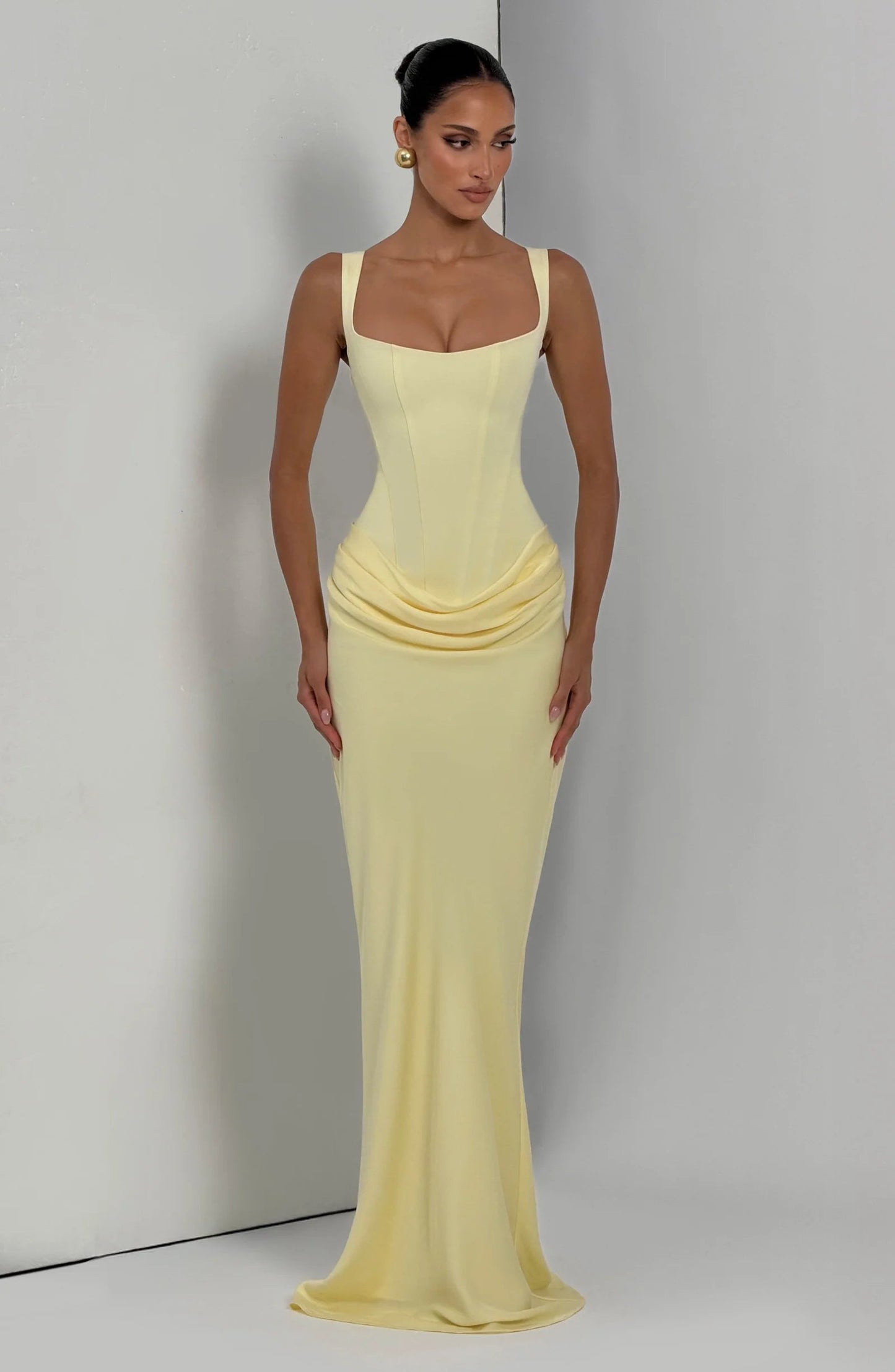 Full-length yellow draped maxi dress on neutral backdrop, corset bodice and soft pooling skirt